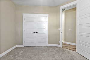 Unfurnished bedroom featuring light colored carpet and a closet