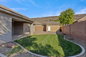 Fenced backyard with a patio area, a storage unit, and a mountain view