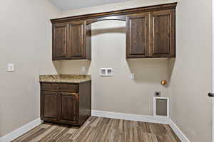 Laundry area with cabinet space, hookup for a washing machine, light wood-type flooring, and hookup for an electric dryer