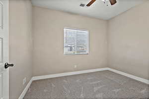Carpeted empty room featuring baseboards and a ceiling fan