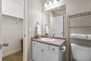 Bathroom with vanity, carpet flooring, and a walk in closet