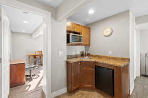 Kitchen with light carpet, recessed lighting, brown cabinets, black refrigerator, and stainless steel microwave