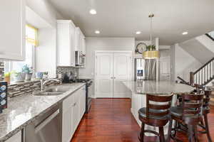Kitchen featuring light stone counters, a kitchen bar, white cabinetry, and recessed lighting
