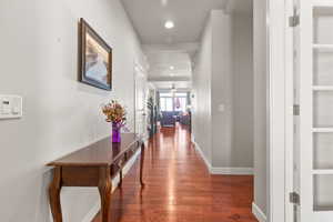 Hall with dark wood finished floors and recessed lighting