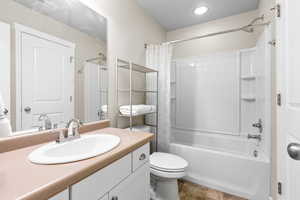 Bathroom featuring shower / bath combo with shower curtain, vanity, and light tile patterned floors