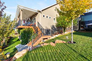 Back of property with a lawn, a deck, stucco siding, and stairway