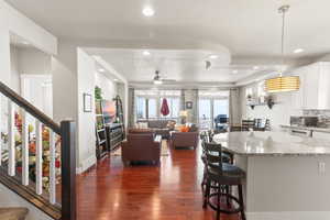 Kitchen with white cabinetry, light stone countertops, a textured ceiling, dark wood-type flooring, and a kitchen breakfast bar