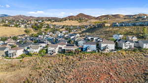 Aerial view of property and surrounding area featuring a mountainous background and nearby suburban area