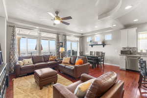 Living room featuring dark wood-style floors, ceiling fan, a textured ceiling, a raised ceiling, and recessed lighting