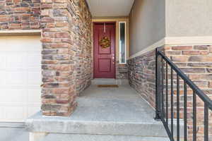 Property entrance featuring stone siding, a garage, and stucco siding