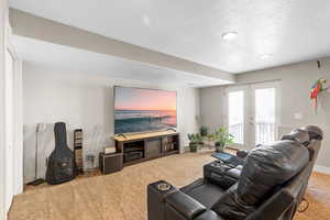 Carpeted living area featuring a textured ceiling and french doors