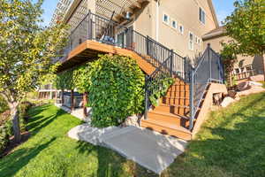 View of grassy yard featuring stairs and a wooden deck