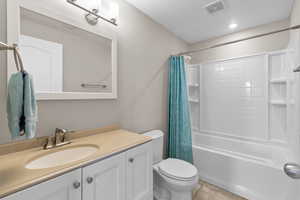 Full bathroom featuring shower / tub combo, vanity, light tile patterned floors, and a textured ceiling