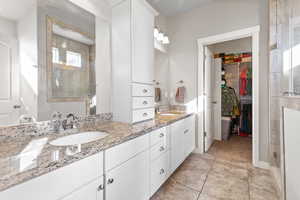 Bathroom with a shower stall, a spacious closet, double vanity, and light tile patterned floors