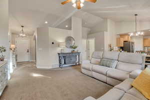 Living area featuring a chandelier, light colored carpet, recessed lighting, ceiling fan, and high vaulted ceiling