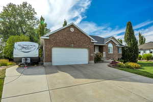 View of front of property with driveway, brick siding, and a garage
