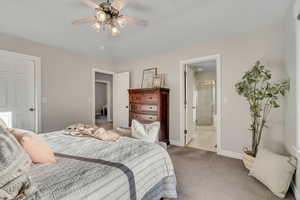 Bedroom with ensuite bath, carpet, and ceiling fan