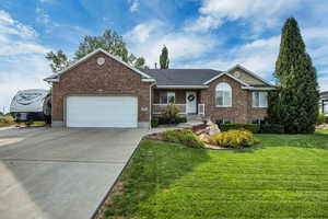 Ranch-style home with brick siding, covered porch, driveway, and a front lawn