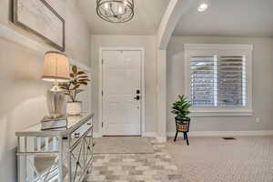 Entrance foyer with a chandelier, recessed lighting, and light carpet