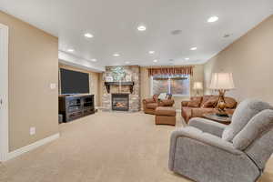 Carpeted living area featuring recessed lighting and a stone fireplace