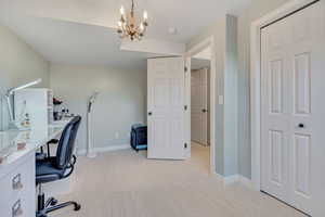 Home office featuring light carpet and a chandelier