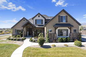 Craftsman-style house with stone siding, a standing seam roof, a front yard, and a metal roof