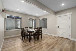 Dining area with beam ceiling, light wood-style floors, and recessed lighting