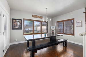 Dining space with dark wood-style floors and a chandelier