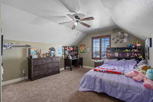 Carpeted bedroom with vaulted ceiling, a textured ceiling, and a ceiling fan