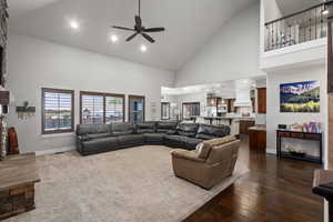Living area with high vaulted ceiling, a stone fireplace, recessed lighting, dark wood-style floors, and ceiling fan