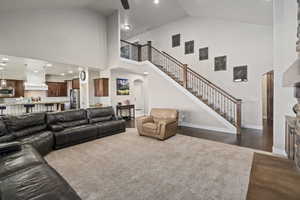 Living area featuring high vaulted ceiling, dark wood finished floors, recessed lighting, stairway, and a ceiling fan