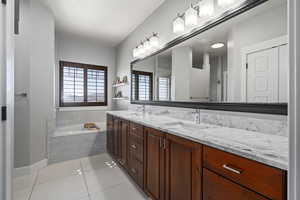 Full bathroom with double vanity, a garden tub, and light tile patterned floors