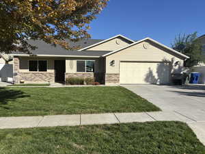 Single story home with brick siding, a front yard, an attached garage, and concrete driveway