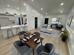 Dining room with recessed lighting, light wood-type flooring, and high vaulted ceiling