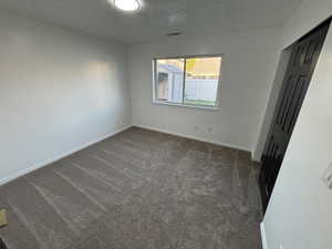 Empty room with dark colored carpet and a textured ceiling