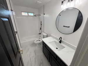 Bathroom with a textured ceiling, shower / washtub combination, vanity, and light marble finish floors