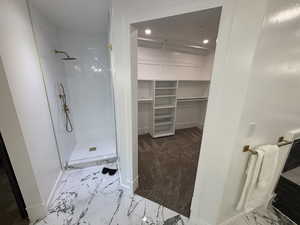 Bathroom featuring a shower stall, marble finish floors, recessed lighting, and a spacious closet