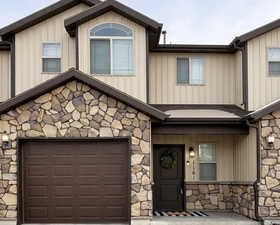 Craftsman inspired home featuring stone siding, covered porch, and a garage