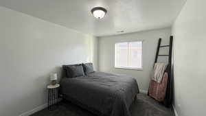 Bedroom featuring a textured ceiling and dark carpet