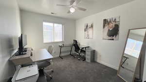 Office featuring dark carpet, ceiling fan, and a textured ceiling