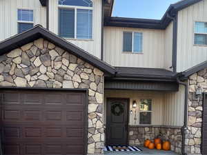 Craftsman-style home featuring stone siding, driveway, board and batten siding, and covered porch