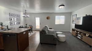 Living room featuring healthy amount of natural light, a textured ceiling, dark tile patterned floors, and a chandelier
