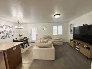 Living area featuring a textured ceiling, a chandelier, and dark tile patterned flooring