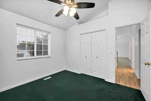 Upstairs bedroom featuring vaulted ceiling, carpet flooring, ceiling fan, and a closet