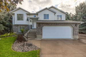 Bi-level home with brick siding, concrete driveway, a garage, and a shingled roof