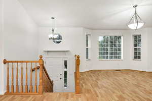 Foyer entrance featuring light wood-type flooring, a chandelier, and stairway