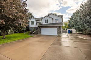 Split foyer home featuring brick siding, driveway, an attached garage, a shingled roof, and a front yard