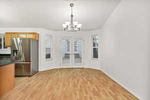 Dining area featuring light wood-style flooring, french doors, and a chandelier