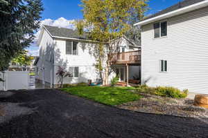 Rear view of property with a gate, a yard, a wooden deck, and a patio area