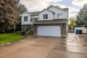 View of front of property featuring brick siding, concrete driveway, roof with shingles, and a garage